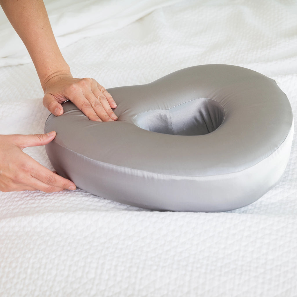 Charcoal Longevity Pillow being held by a person on a white bed