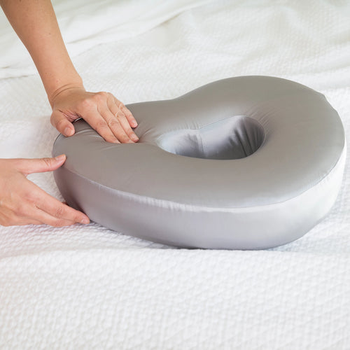 Charcoal Longevity Pillow being held by a person on a white bed